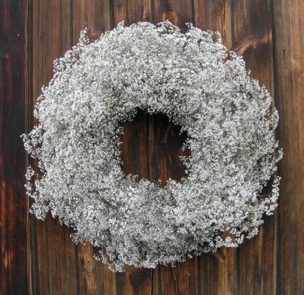 A white snowflake wreath hanging on a wooden wall.