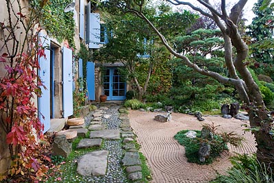 A stone pathway leads to a house with blue shutters.
