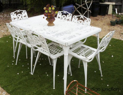 A white wrought iron table and chairs in a garden.
