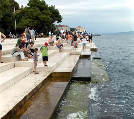 A group of people sitting on steps near the water.