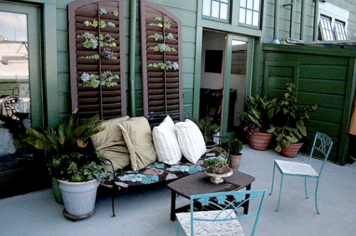 A patio with green shutters and furniture.