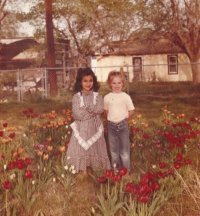 Two children standing in a field of tulips.