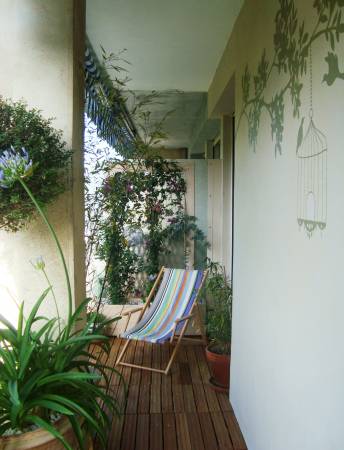 A balcony with a chair and potted plants.