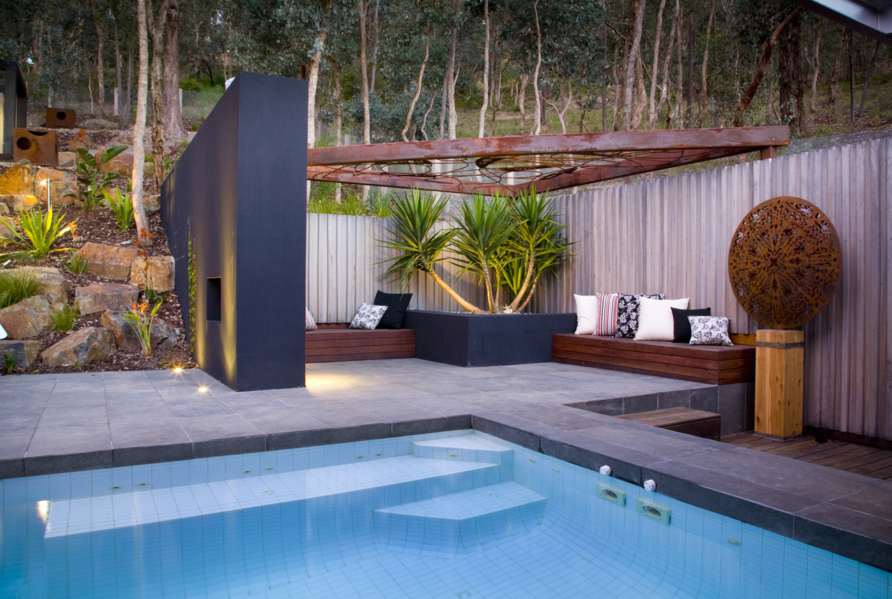 A modern backyard with a pool and a wooden deck.