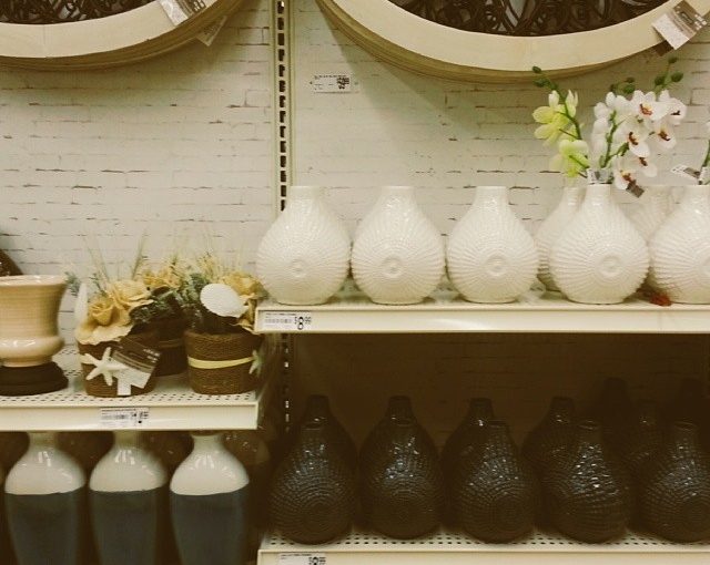 A shelf full of vases and pots in a store.