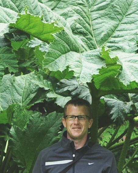 A man standing in front of a large plant.