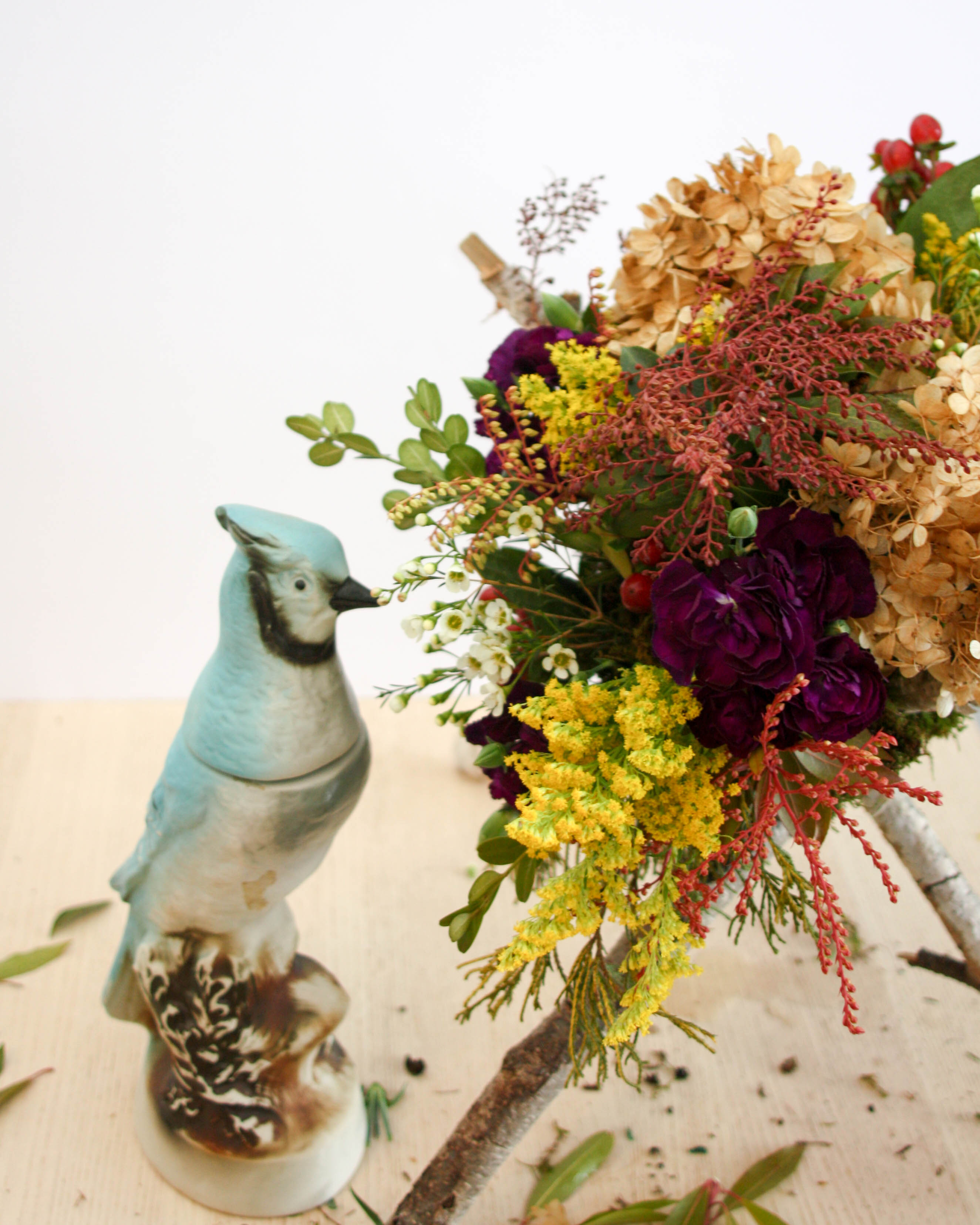 A vase with flowers and a bird on it.