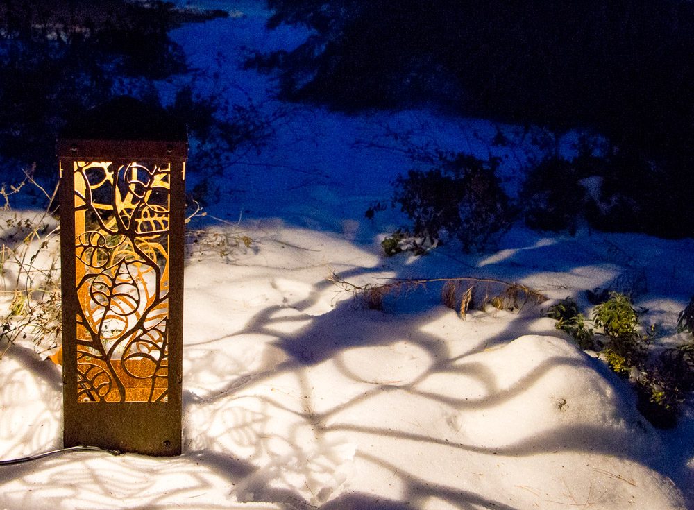Shadows of an artistic garden light on the winter snow