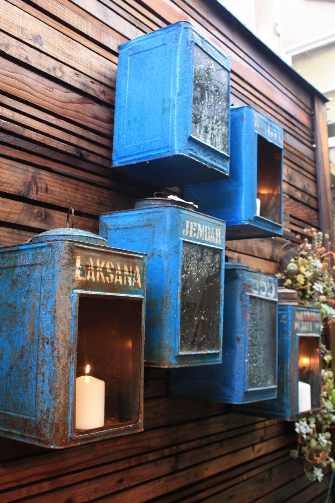 Aged metal boxes mounted on a fence as candle holders in a garden