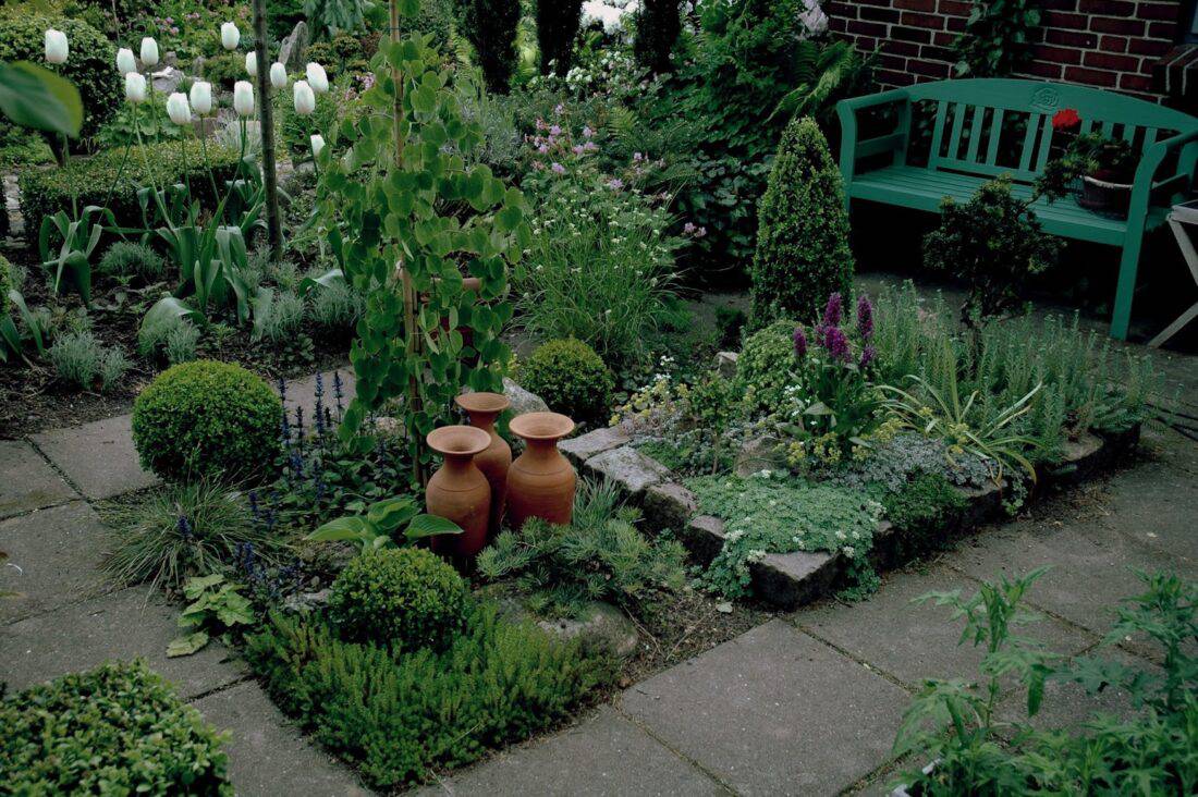 terracotta pots and a green bench in a garden