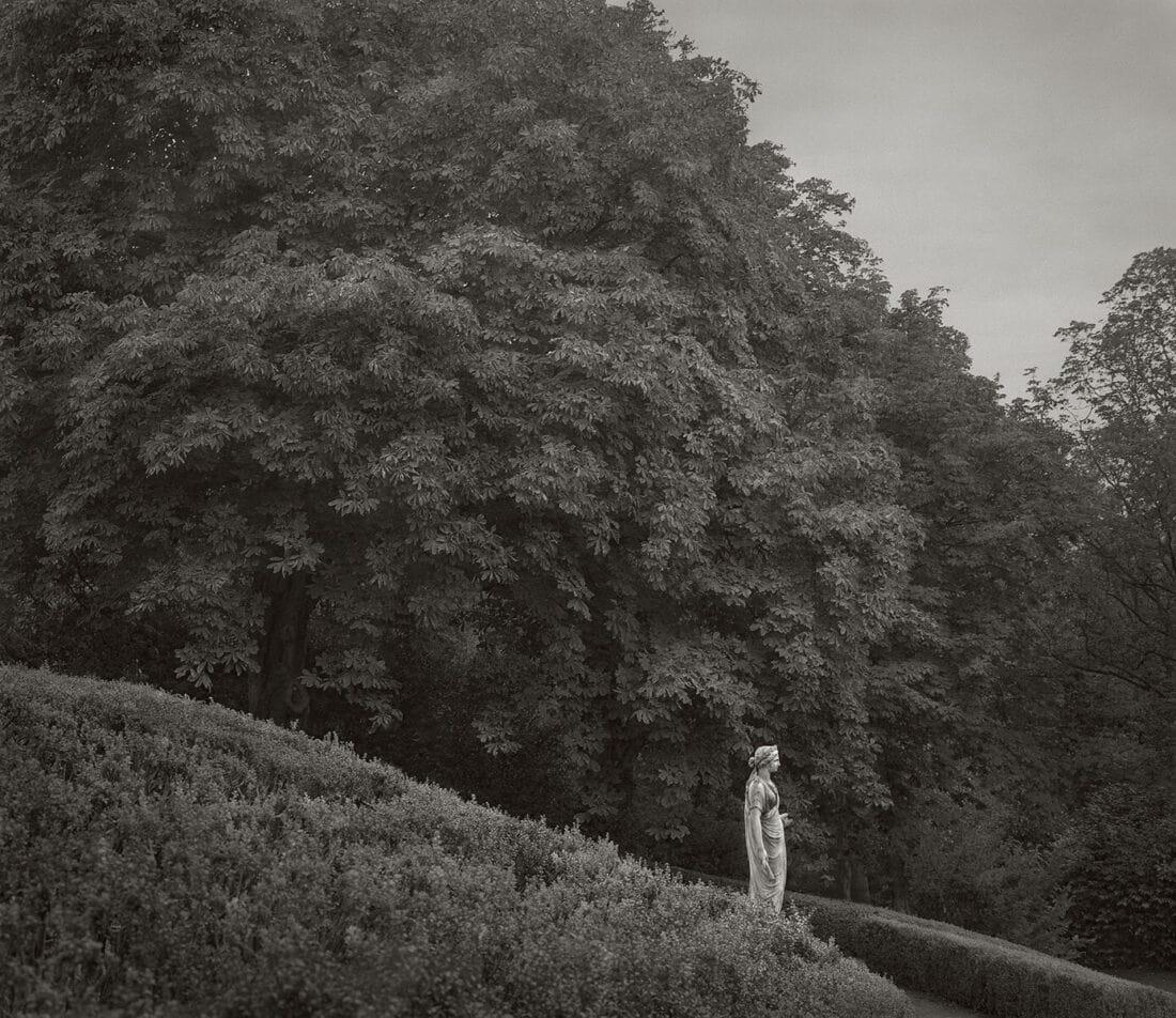 A black and white photo of a woman standing on a hill.