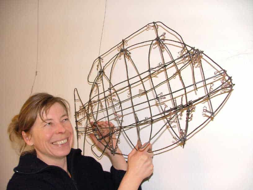 A woman holding up a wire sculpture.