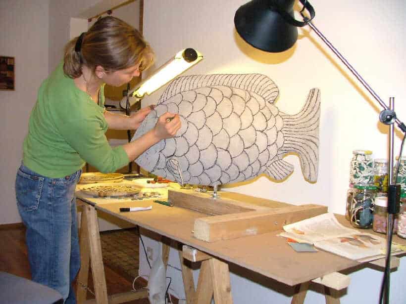 A woman working on a fish sculpture.