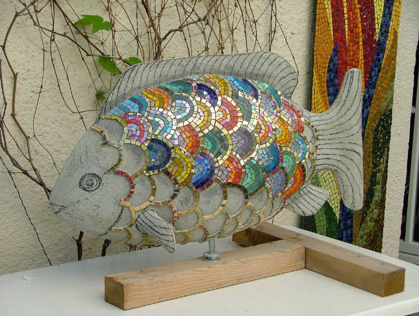 A mosaic fish sculpture on a wooden stand.