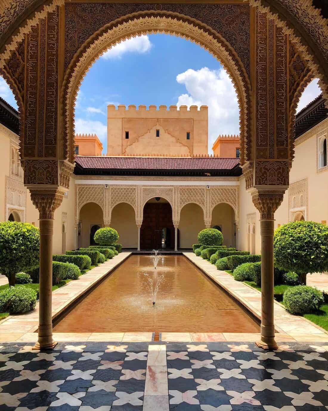 A courtyard with a fountain and arches.