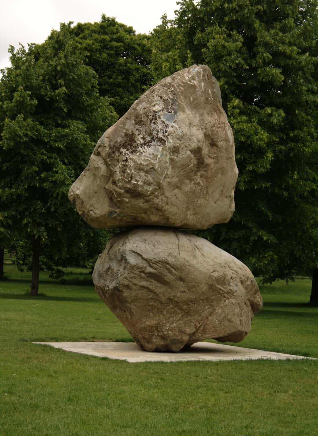 A large rock in the middle of a grassy field.