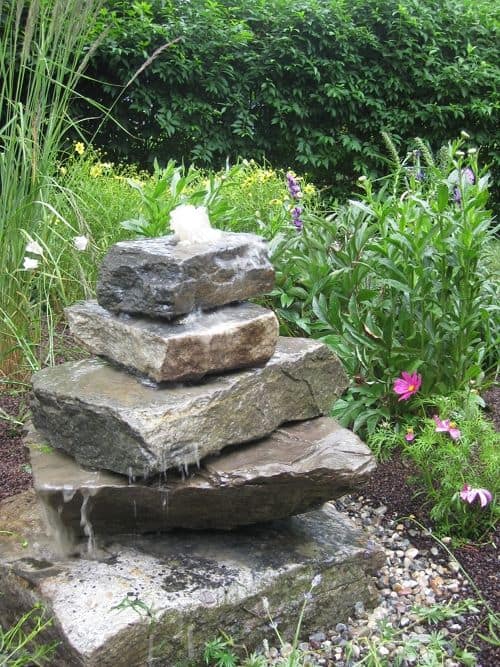 A water fountain made of rocks in a garden.