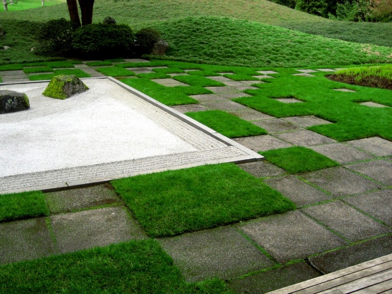 A japanese garden with green grass and stones.