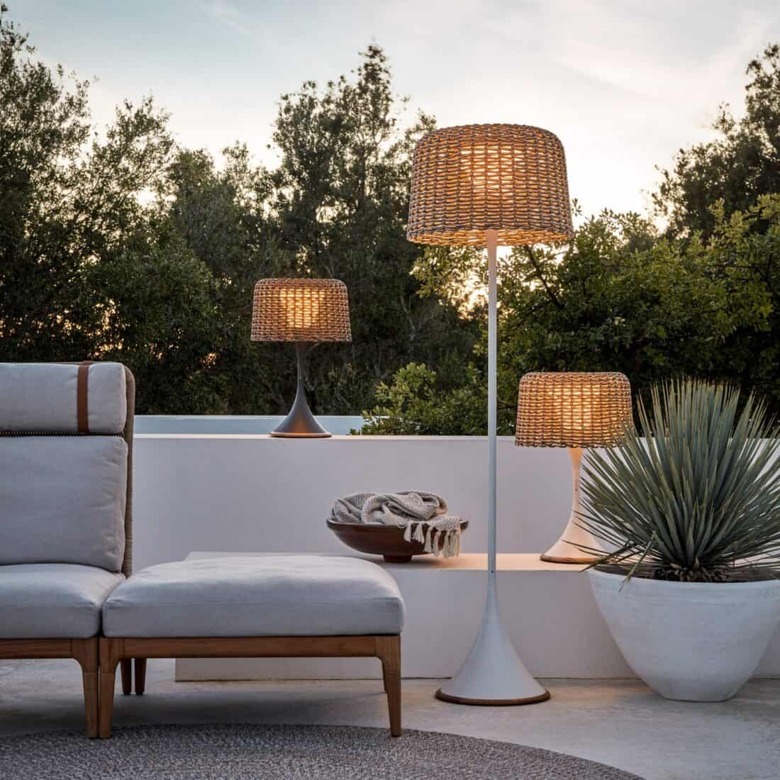 A lounge chair and wicker lamp on a patio.