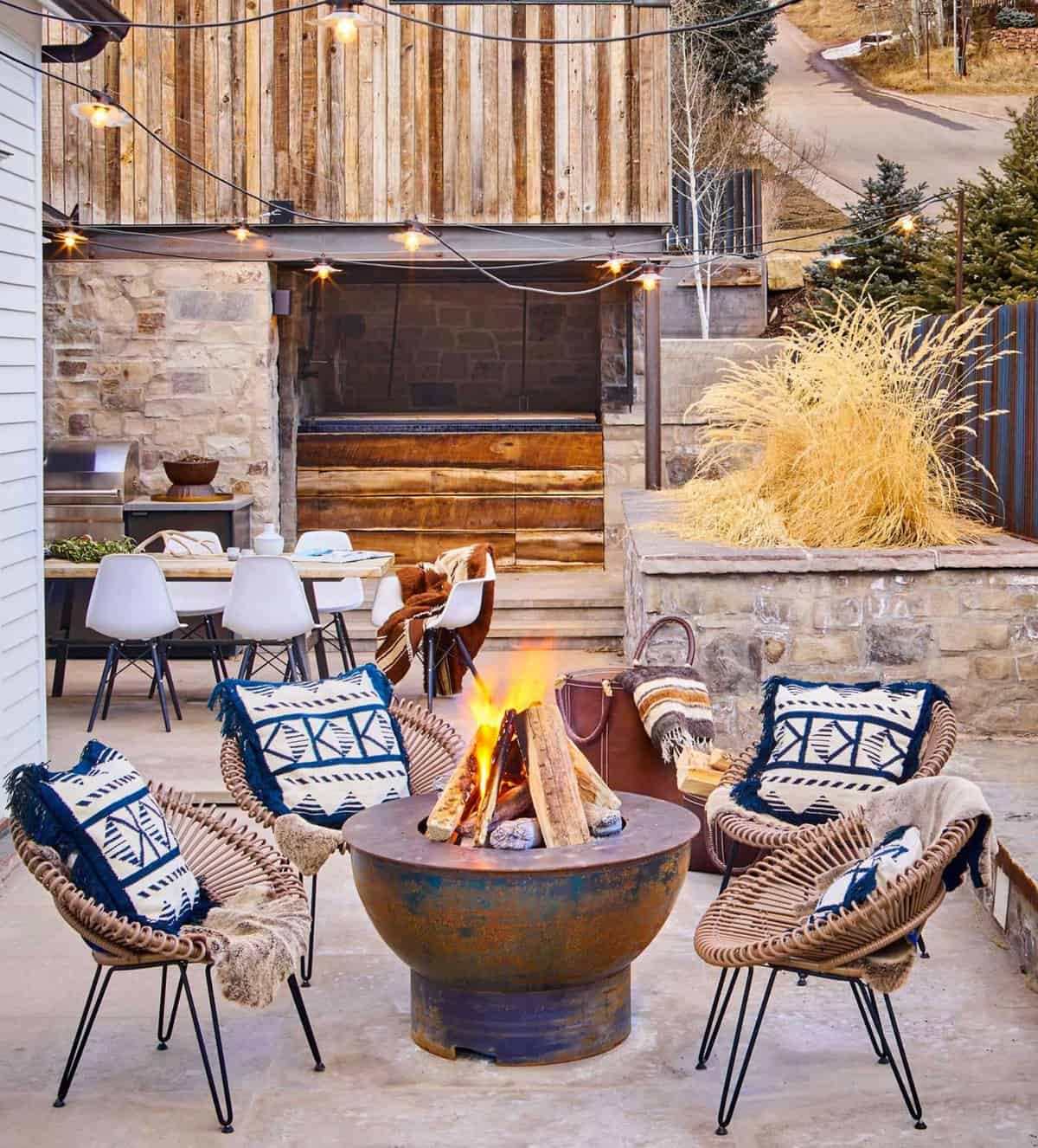A patio with a fire pit and chairs.