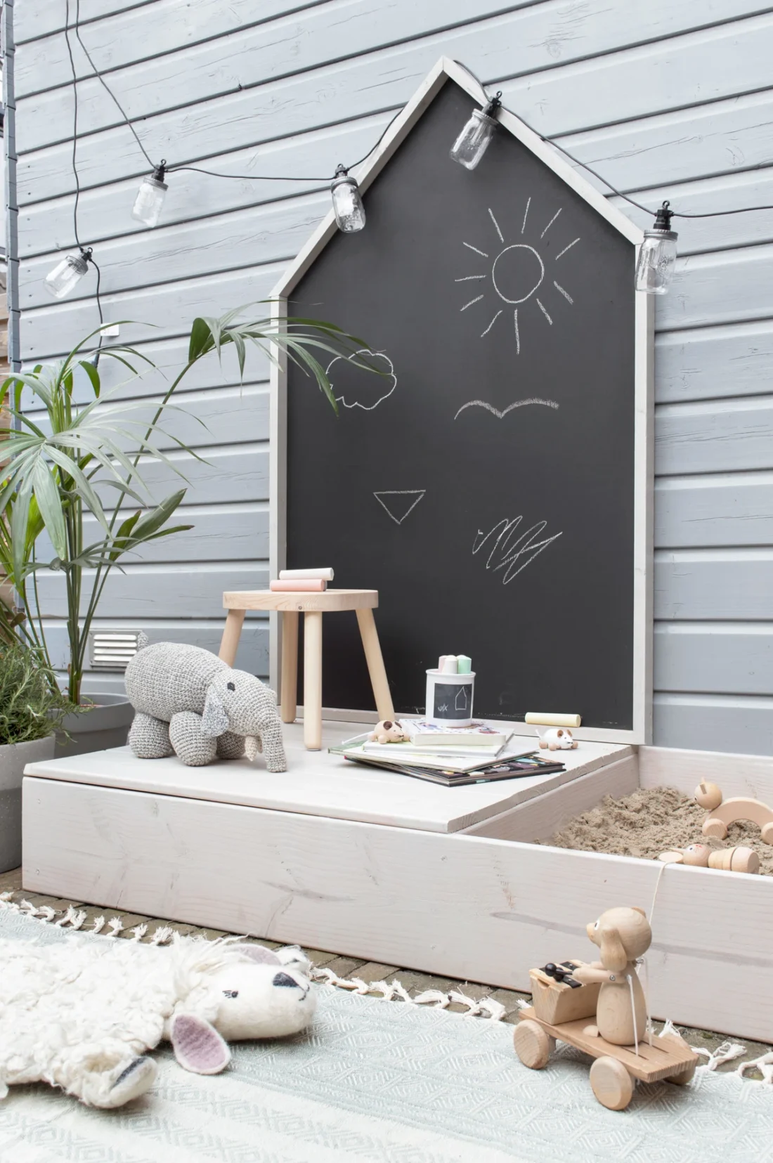 A sandbox with toys and a chalkboard.