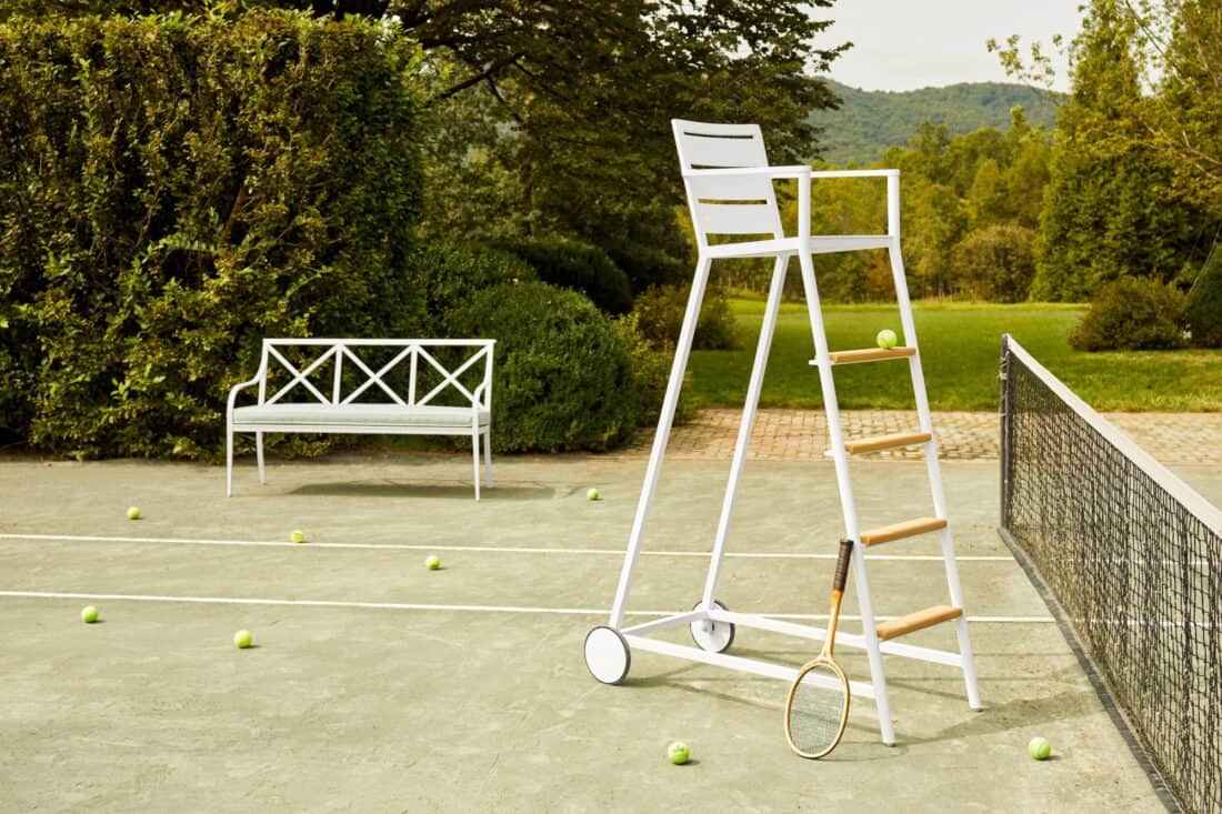 A tennis court with a bench and tennis balls.