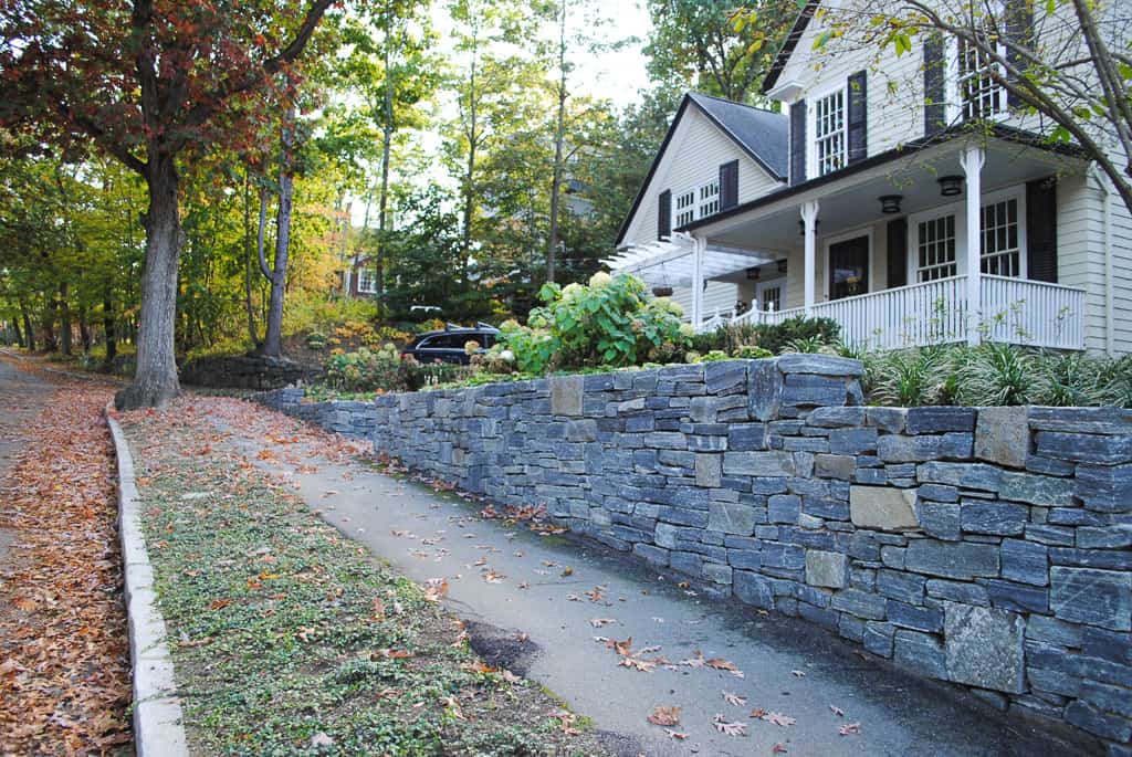A stone wall next to a house.