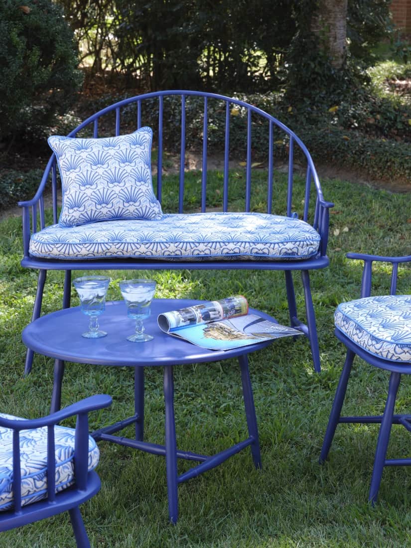 A blue metal chair with a blue cushion and a magazine on a table.