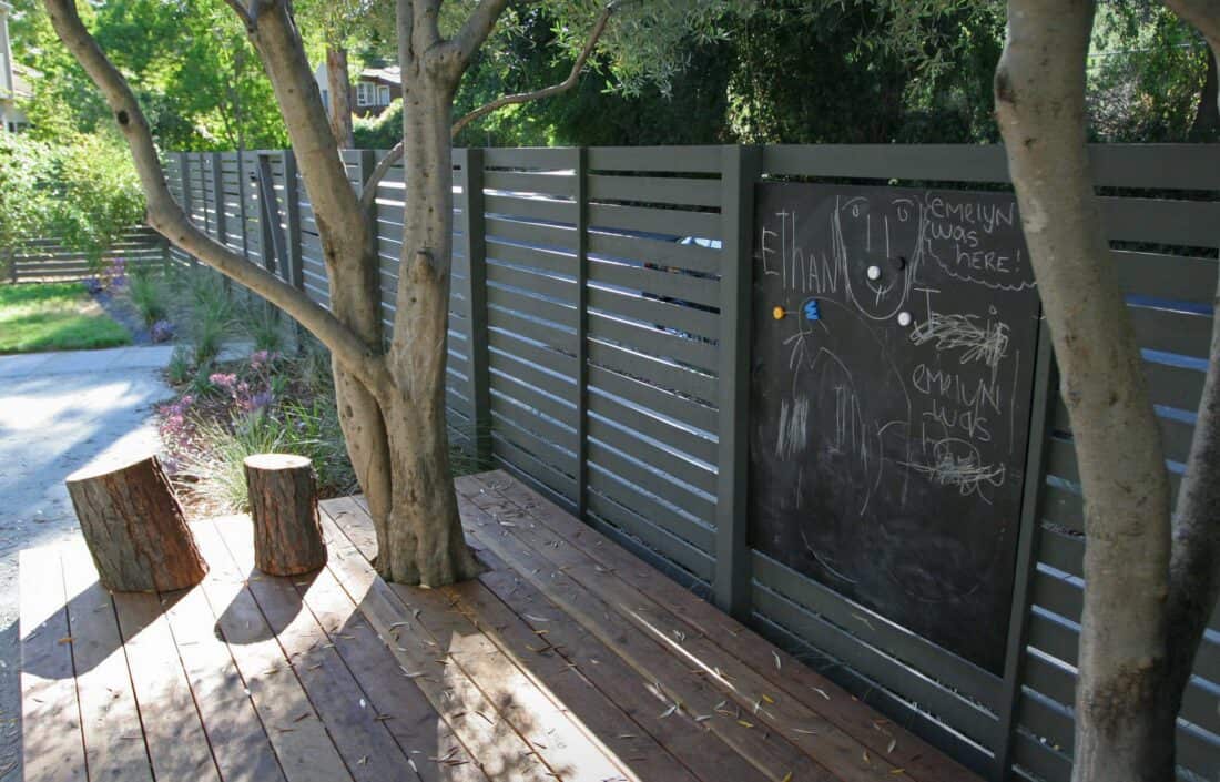 A wooden deck with a tree and a chalkboard.