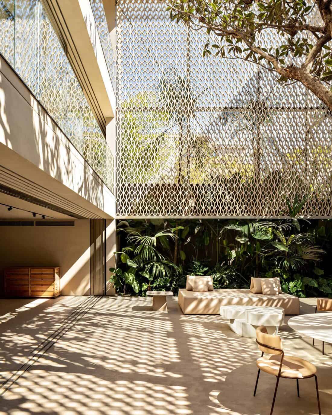 A courtyard in a building with a tree in the middle. Filligree breeze blocks by arthur casas design.
