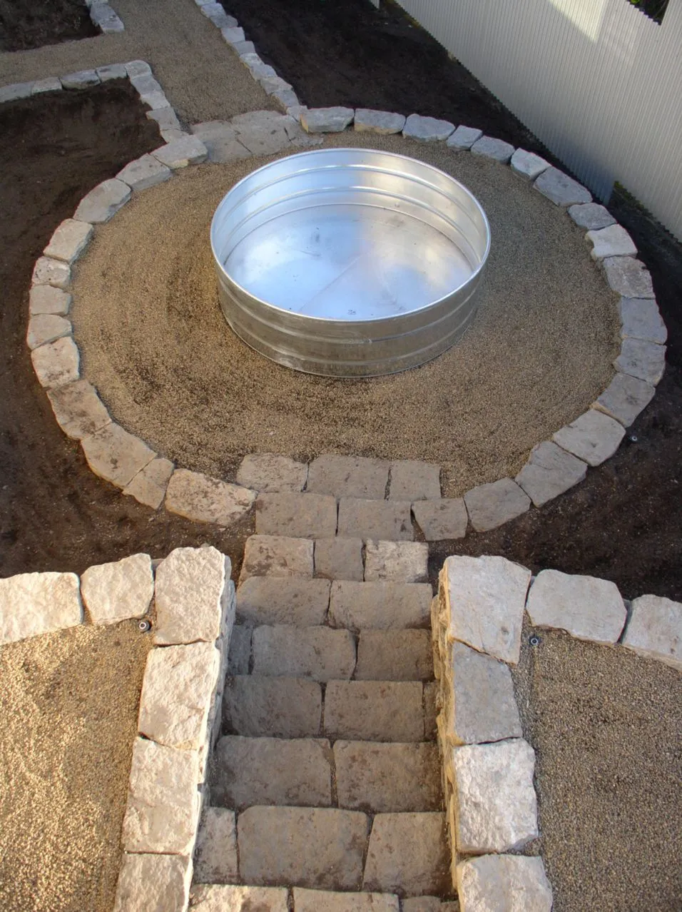 Circular metal fire pit centered within a patterned stone patio.