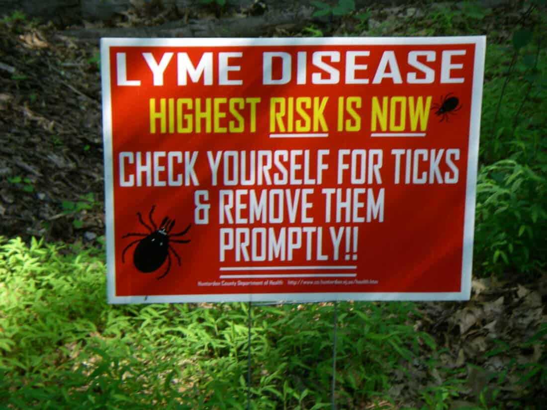Warning sign alerting about the high risk of lyme disease and advising to check for and remove ticks promptly, utilizing Lyme resources.