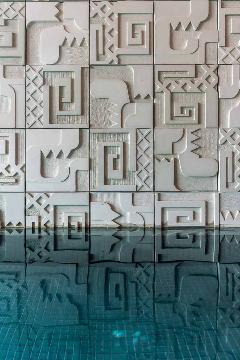 Decorative geometric wall panels reflected on a calm water surface, creating a symmetrical visual effect.