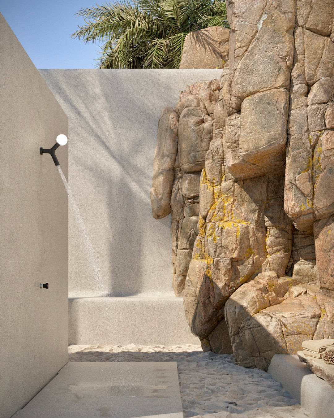 Exterior walkway next to a textured rock formation, perfect for outdoor shower ideas, with a stark white wall on the left equipped with a modern light fixture. The ground has sandy paving stones leading into
