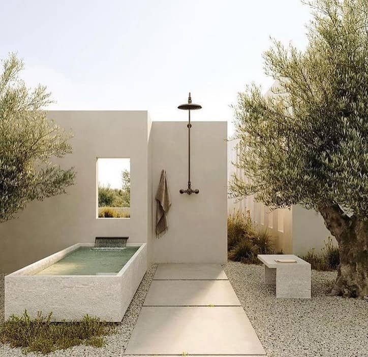 Minimalist outdoor shower ideas and bath setup with cubic structures surrounded by olive trees in a serene, landscaped environment.